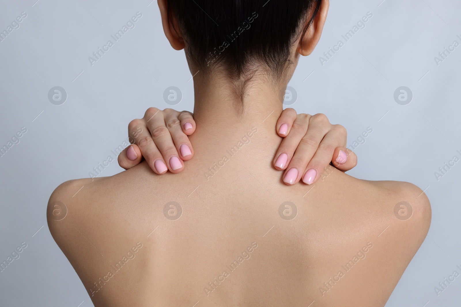 Photo of Back view of woman with perfect smooth skin on light background, closeup