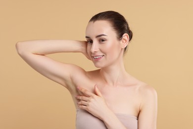 Beautiful woman showing armpit with smooth clean skin on beige background