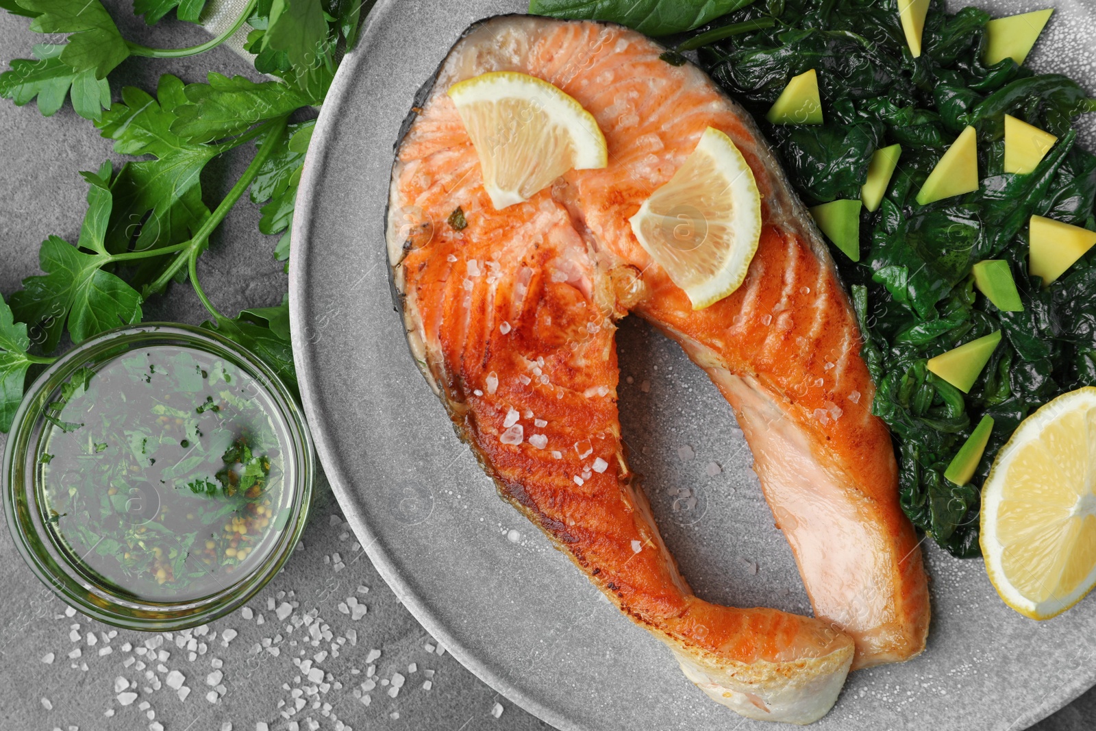 Photo of Tasty salmon with spinach served on grey table, flat lay