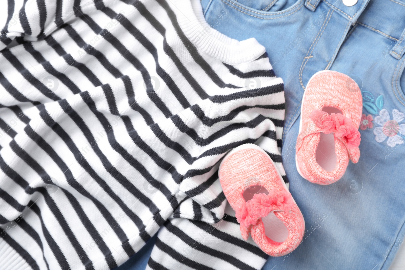 Photo of Pair of cute baby sandals and clothes, top view