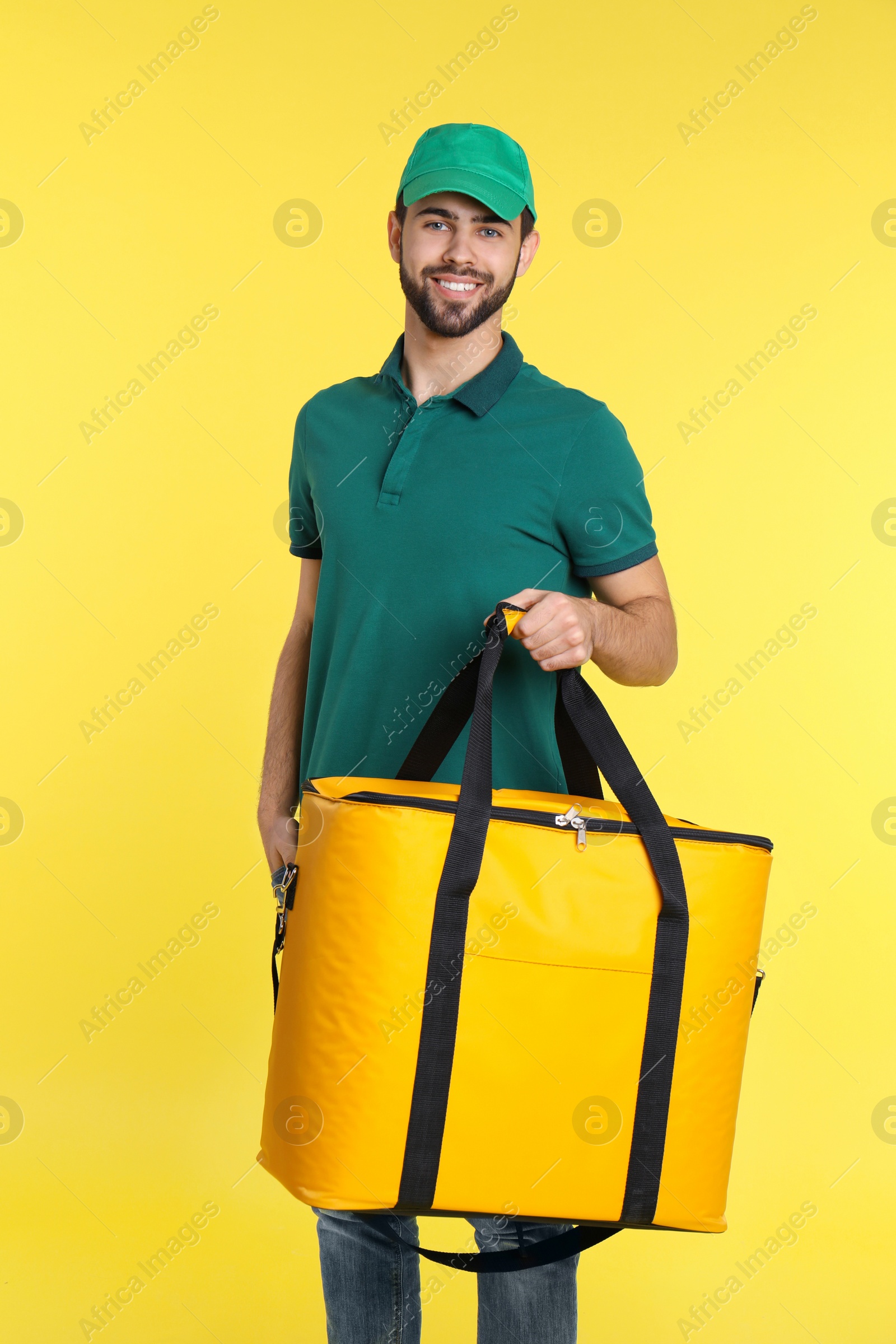 Photo of Young courier with thermo bag on color background. Food delivery service