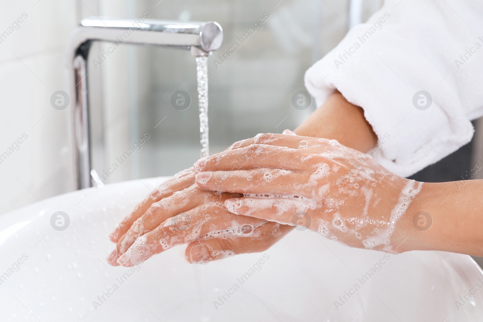 Photo of Woman washing hands with soap over sink in bathroom, closeup