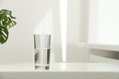 Photo of Glass of water on white table indoors. Space for text