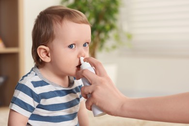 Photo of Mother helping her baby to use nasal spray indoors