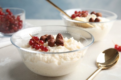 Photo of Creamy rice pudding with red currant and hazelnuts in bowl served on table