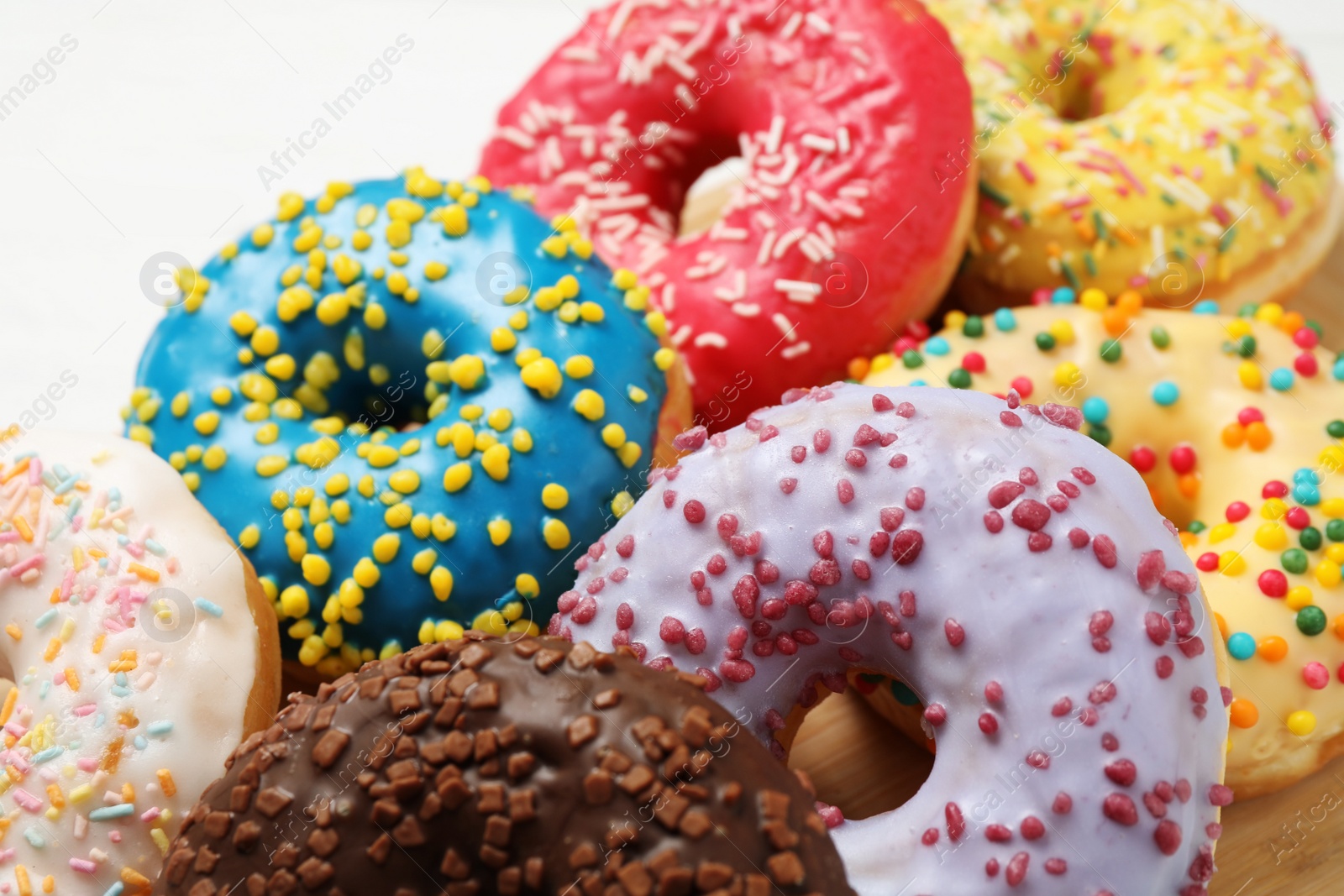 Photo of Yummy donuts with sprinkles on white table, closeup