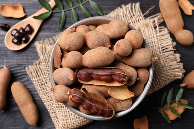 Delicious ripe tamarinds on black wooden table, flat lay