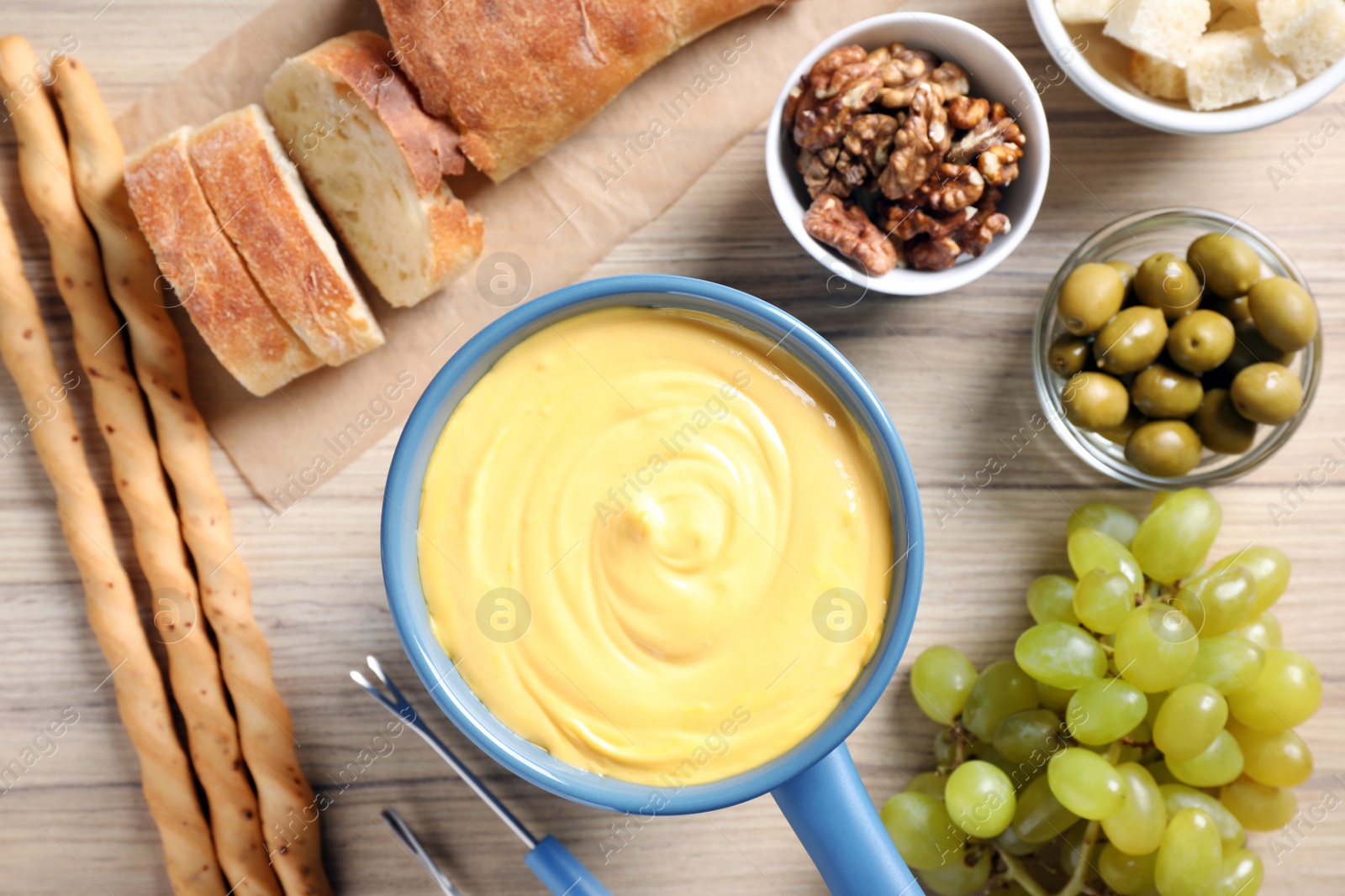 Photo of Flat lay composition with pot of cheese fondue and products on wooden table