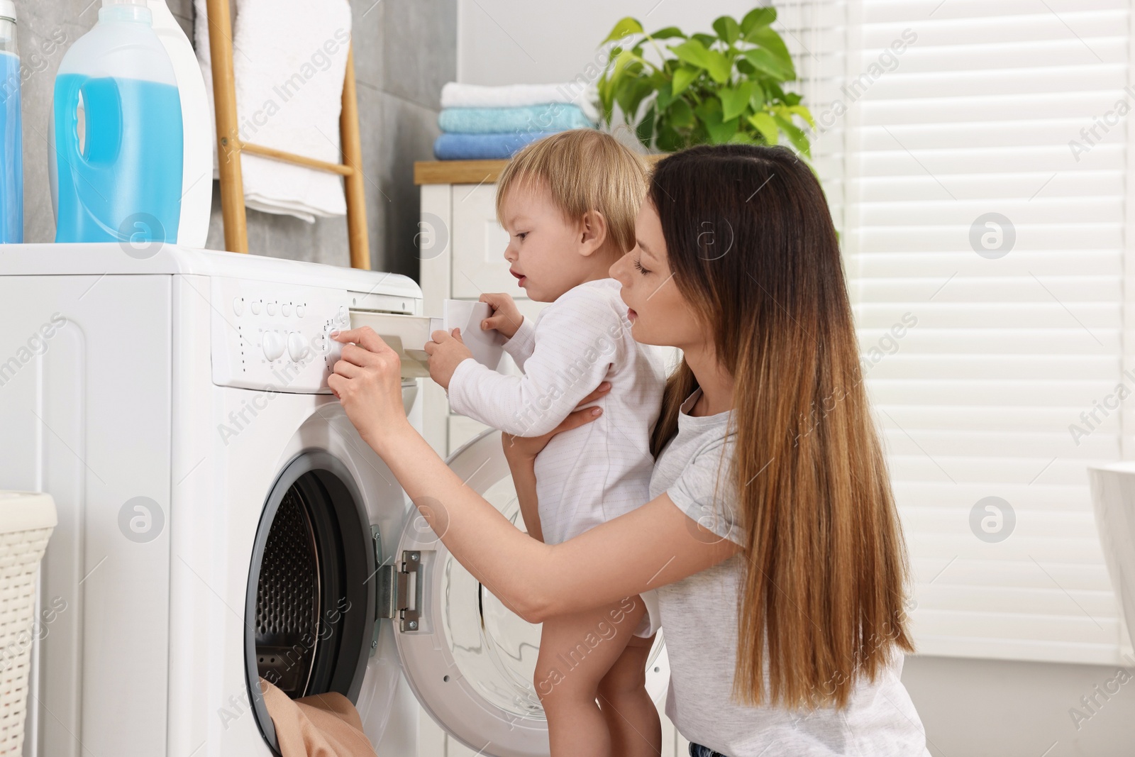 Photo of Mother with her daughter washing baby clothes in bathroom