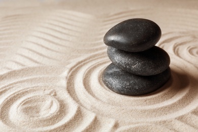 Photo of Stacked zen garden stones on sand with pattern, space for text. Meditation and harmony