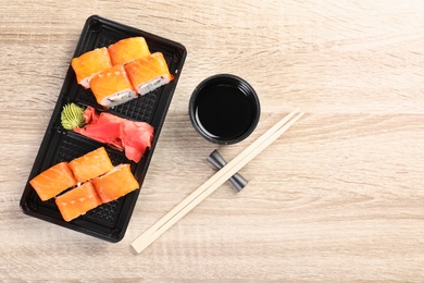 Photo of Tasty sushi rolls served on wooden table, top view with space for text. Food delivery