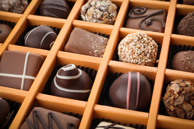 Box with different chocolate candies as background, closeup