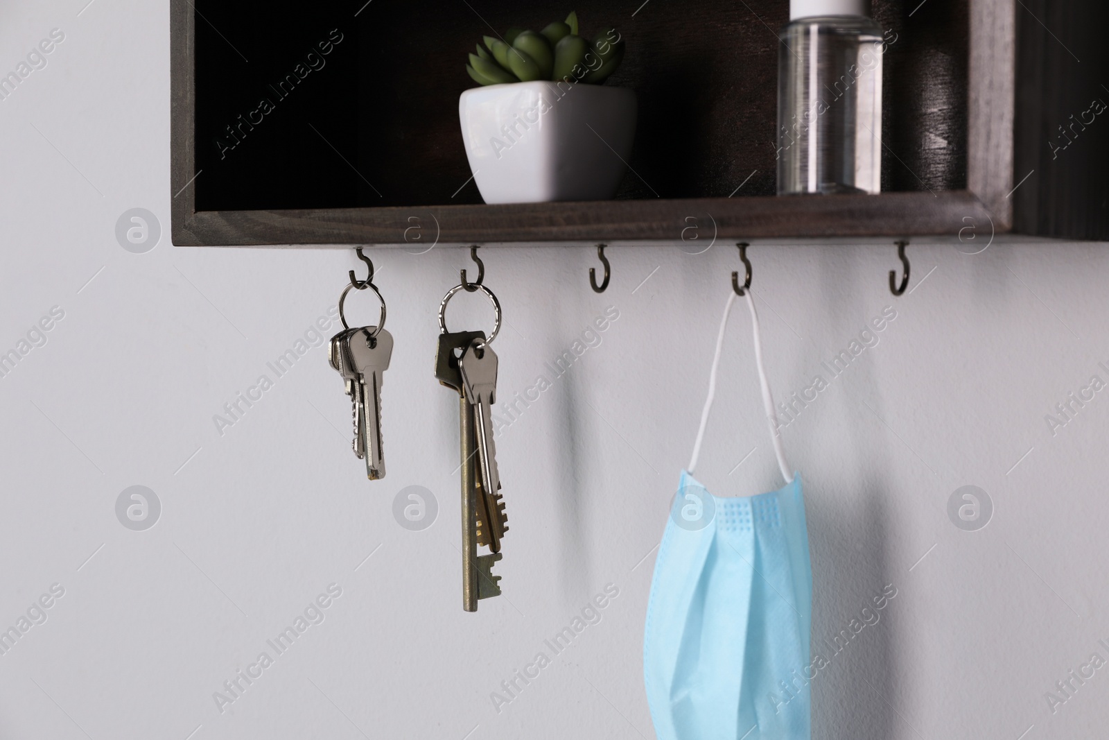 Photo of Wooden hanger for keys with different stuff on light grey wall