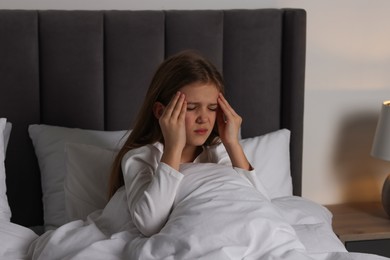 Little girl suffering from headache in bed at night