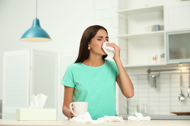 Photo of Young woman suffering from allergy in kitchen