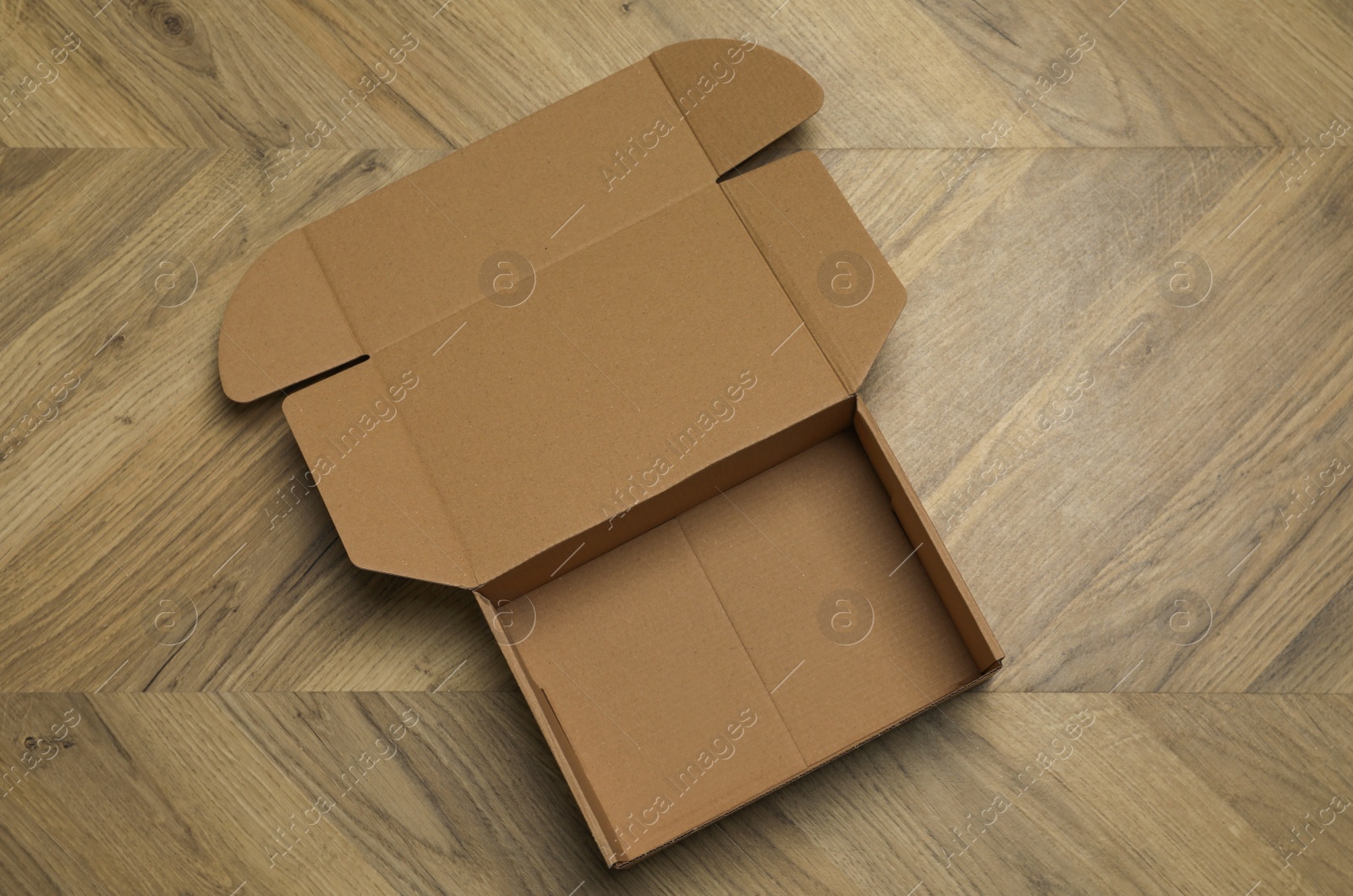 Photo of Empty open cardboard box on floor, top view