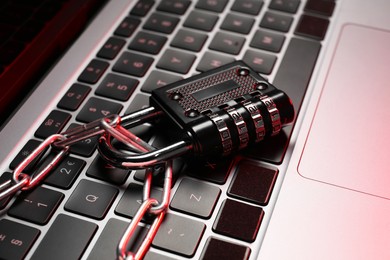 Cyber security. Metal combination padlock with chain on laptop, closeup