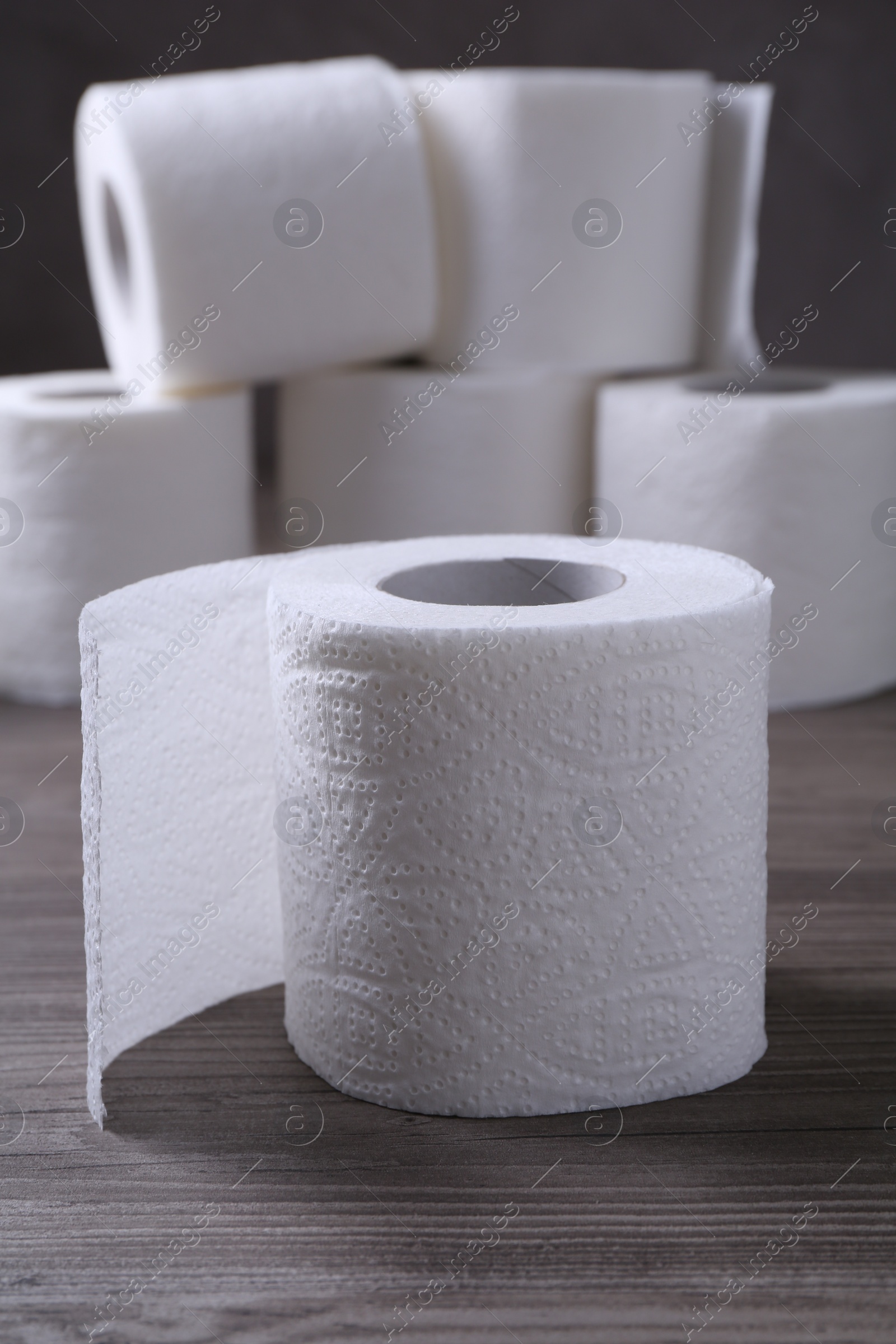 Photo of Soft toilet paper rolls on wooden table, closeup