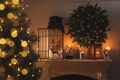 Photo of Beautiful wooden lanterns, festive wreath and other decorations in room with Christmas tree