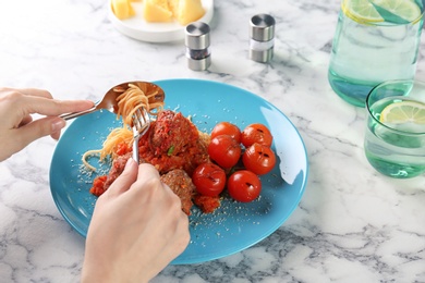 Woman having pasta with meatballs and tomato sauce at table, closeup