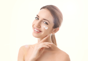 Image of Young woman with sun protection cream on face against white background
