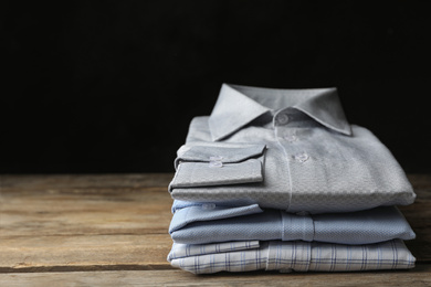 Photo of Stack of classic shirts on wooden table