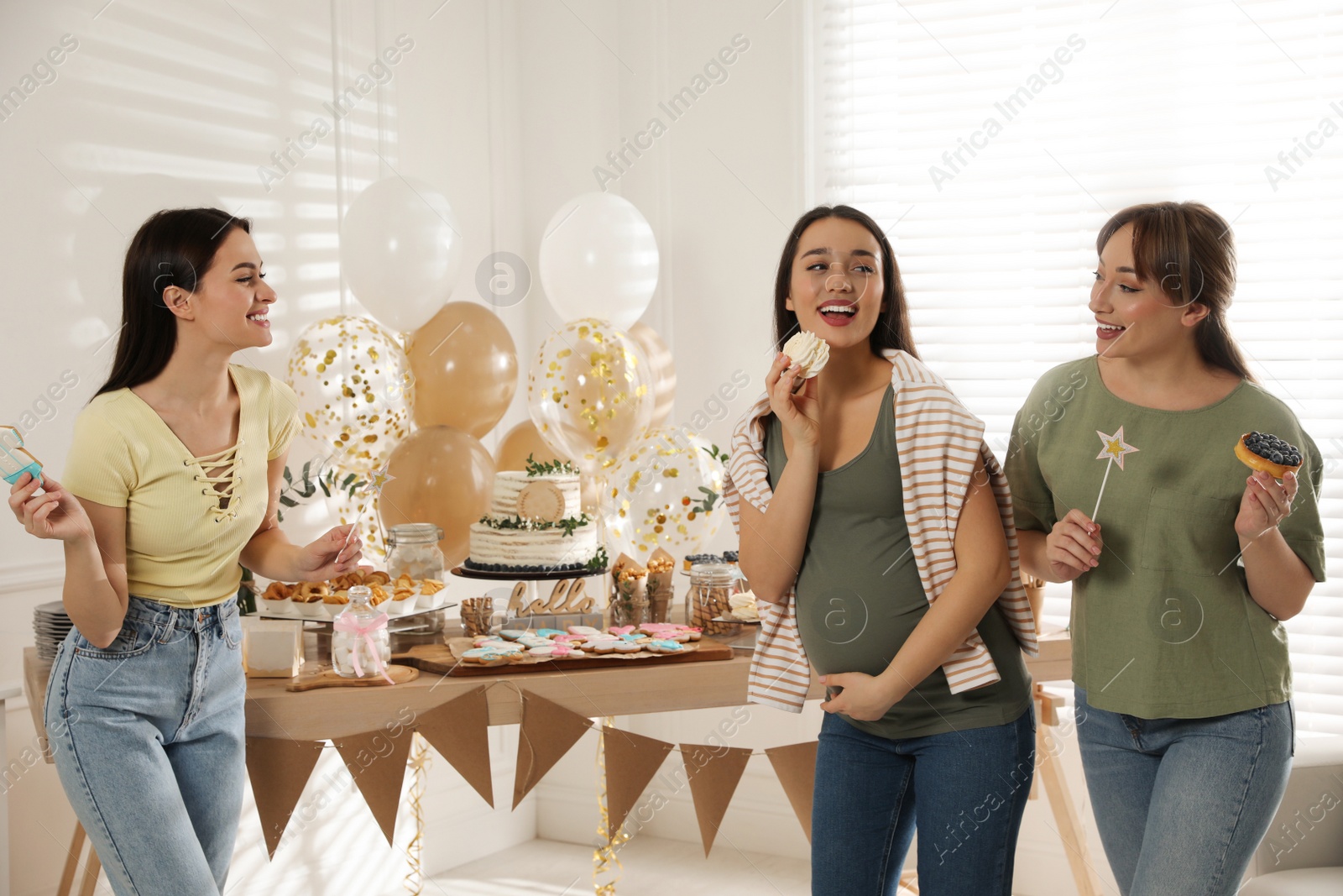 Photo of Happy pregnant woman and her friends with tasty treats at baby shower party