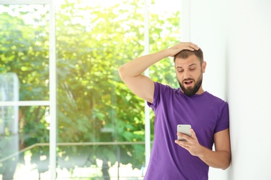 Photo of Portrait of man in casual clothes with smartphone indoors