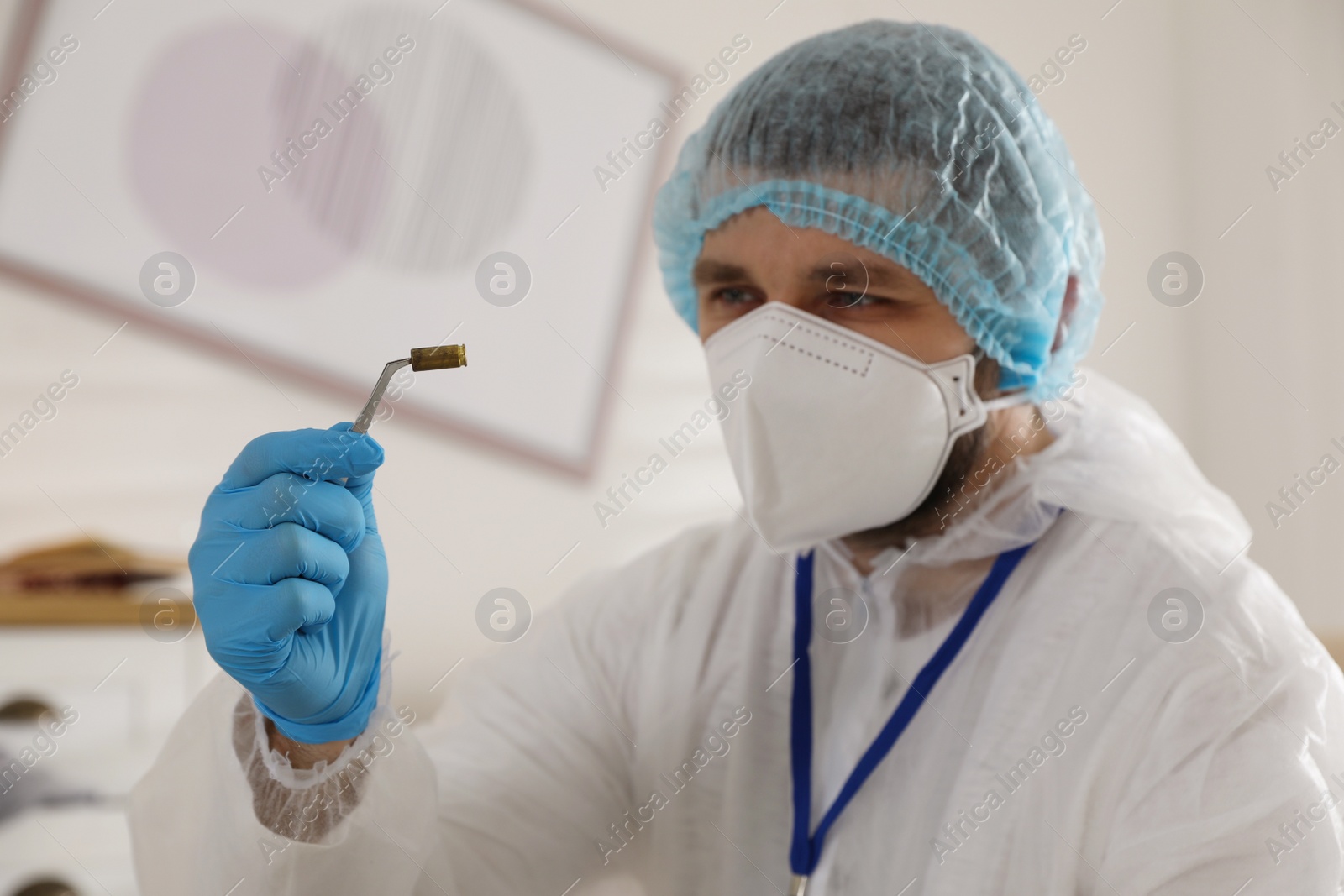 Photo of Investigator in protective suit examining evidence at crime scene indoors