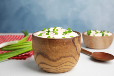 Fresh sour cream with onion on white table against light blue background