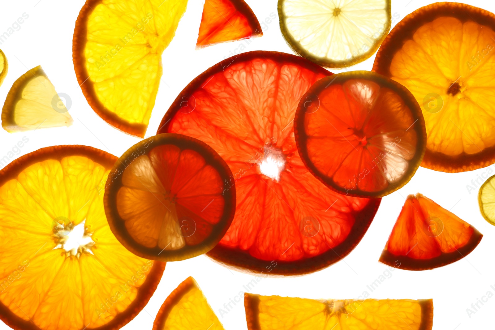 Photo of Illuminated slices of citrus fruits on white background, top view