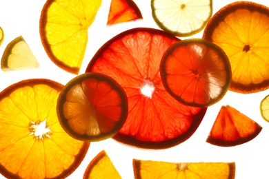 Illuminated slices of citrus fruits on white background, top view