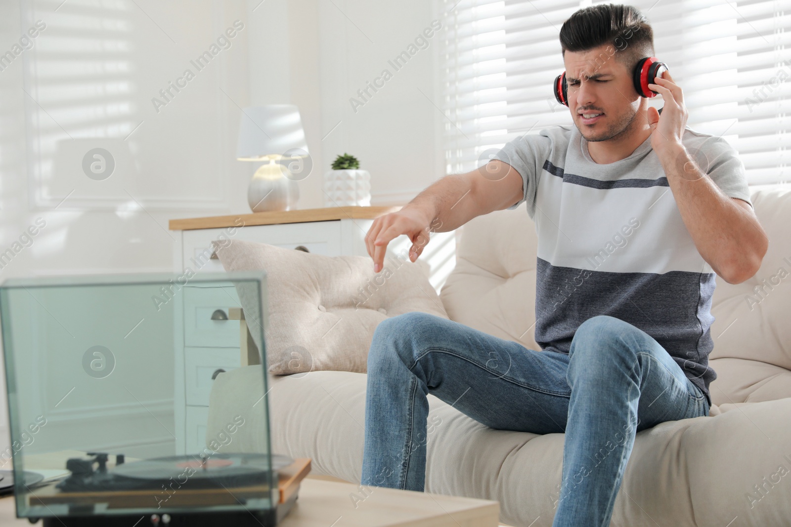 Photo of Emotional man listening to music with turntable at home