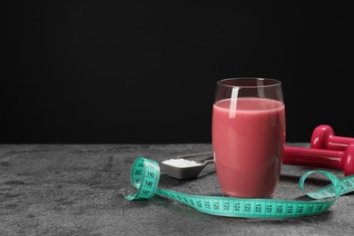 Photo of Tasty shake, measuring tape, dumbbells and powder on stone table against black background, space for text Weight loss