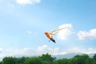 Photo of Person on hang glider flying in sky, space for text