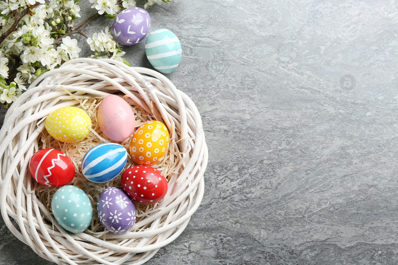 Photo of Flat lay composition with painted Easter eggs and blossoming branches on color background. Space for text