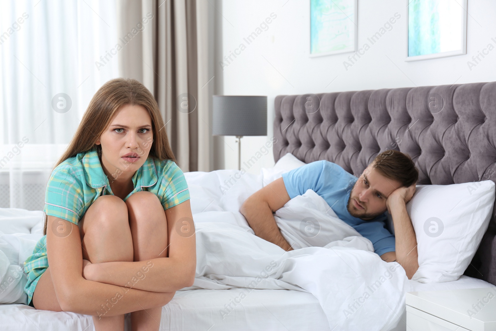 Photo of Upset young couple with relationship problems in bedroom