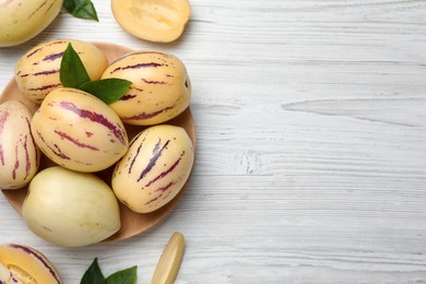 Photo of Whole and cut pepino melons on white wooden table, flat lay. Space for text