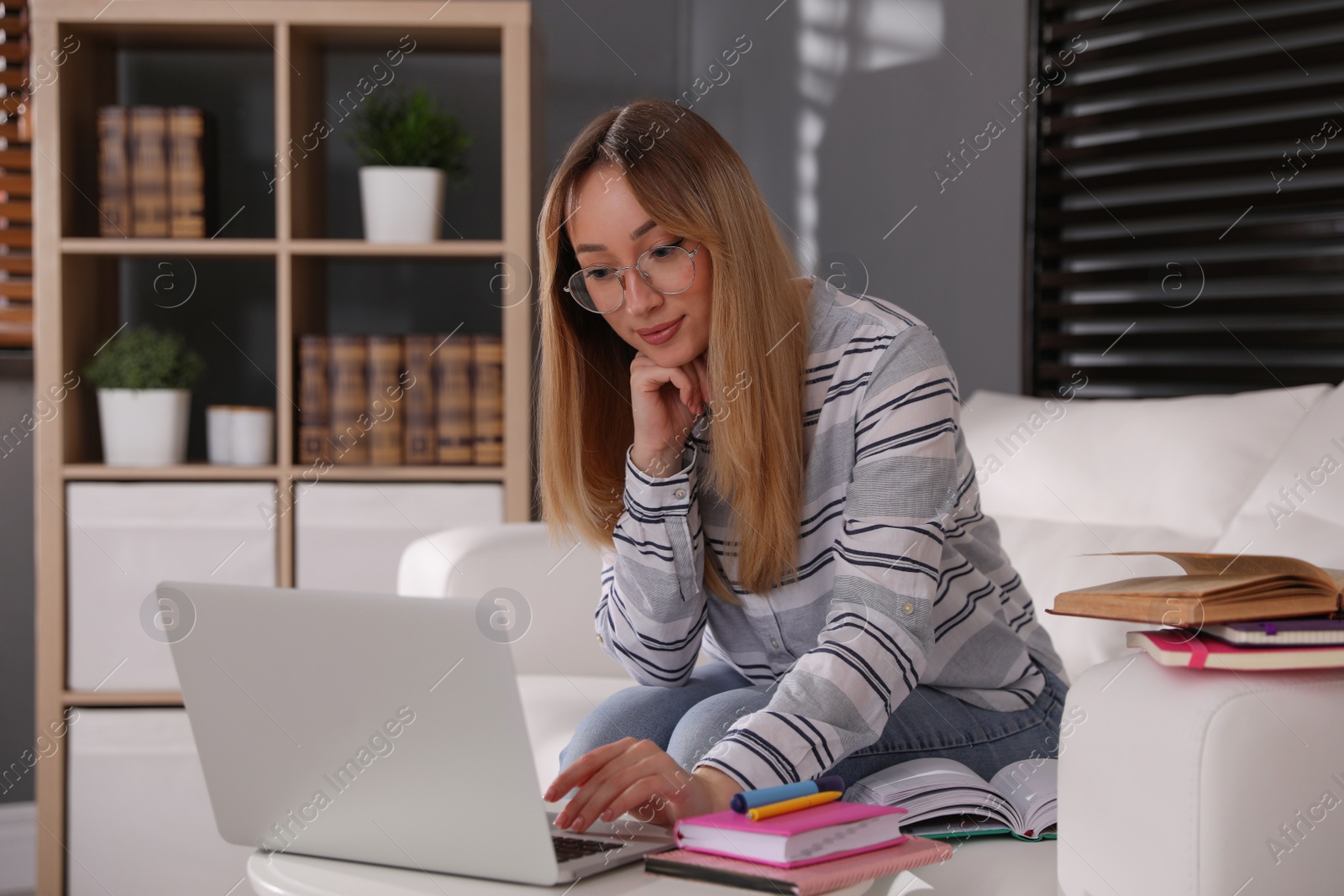 Photo of Young woman watching webinar on sofa at home