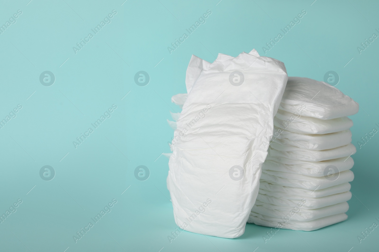 Photo of Stack of diapers on light blue background. Space for text