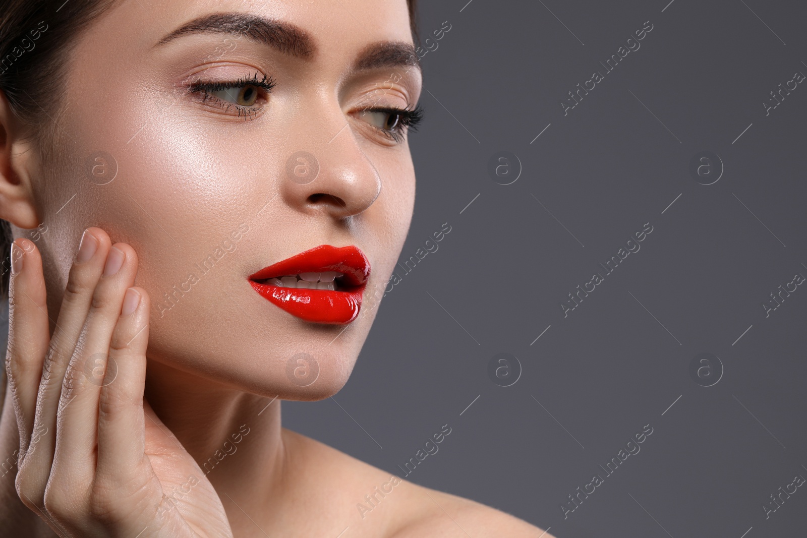 Photo of Young woman with beautiful red lips on grey background. Space for text