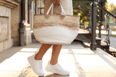 Photo of Young woman with stylish straw bag outdoors, closeup