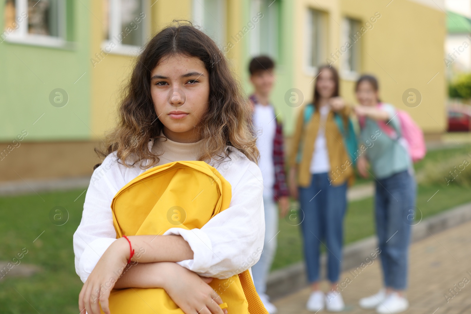 Photo of Teen problems. Students pointing at upset girl outdoors, selective focus