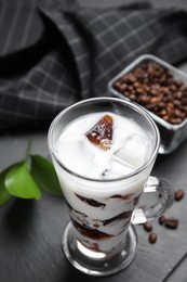 Photo of Glass cup of milk with delicious grass jelly and coffee beans on black table, closeup