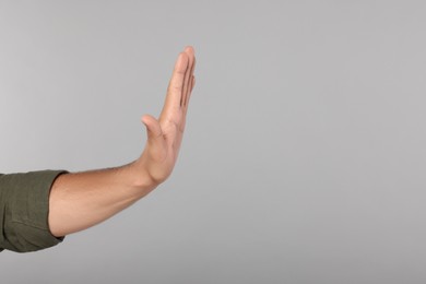 Photo of Man showing stop gesture on light grey background, closeup with space for text