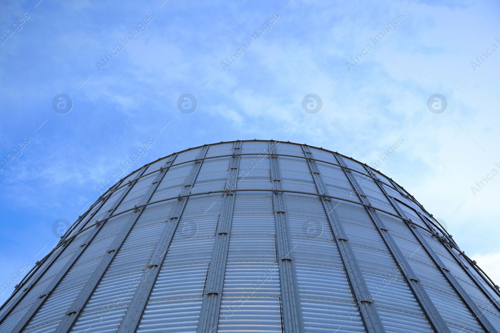 Photo of Modern granary for storing cereal grains against blue sky, low angle view