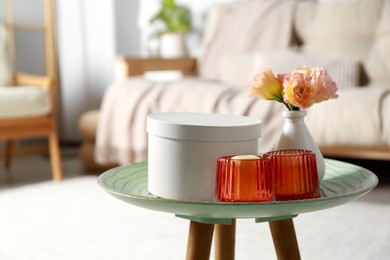 Photo of Box, candles and beautiful flowers on side table at home