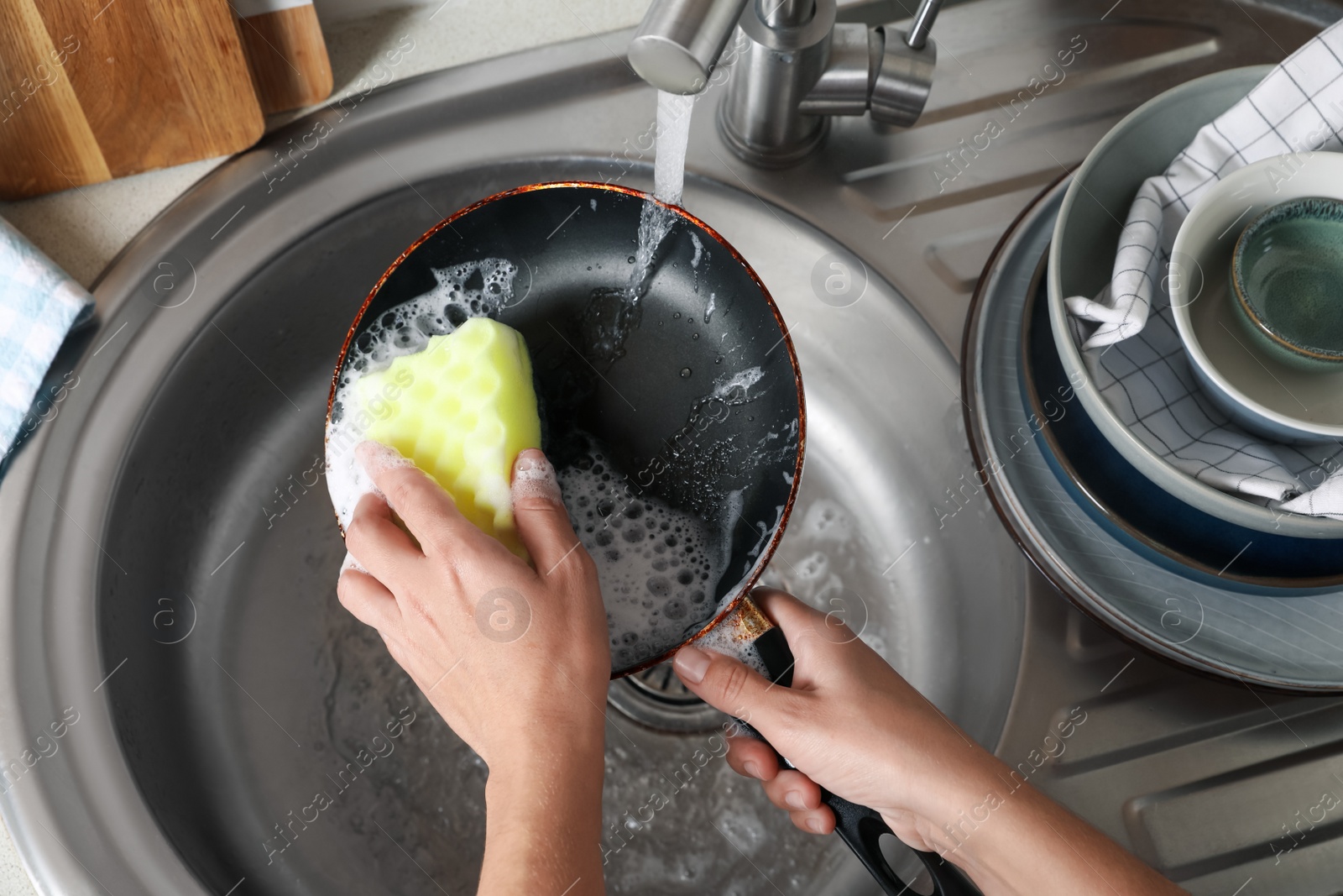 Photo of Woman washing dirty frying pan in sink, above view