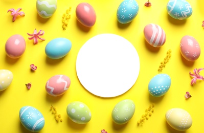 Flat lay composition with painted Easter eggs and blank card on color background, space for text