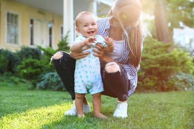 Teen nanny with cute baby on green grass outdoors